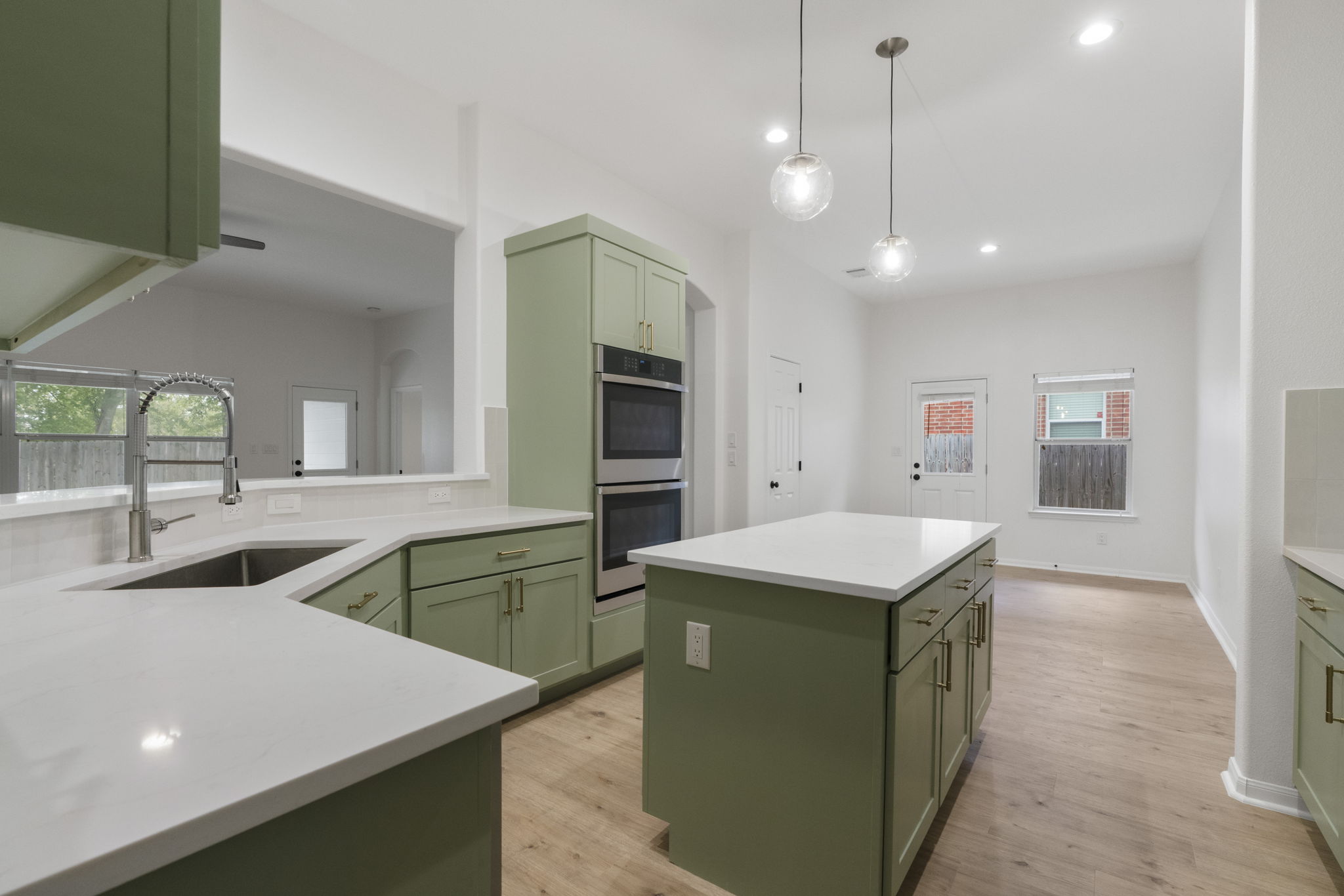 1333 Clary Sage Loop Round Rock, TX 78665 - Photo 7 of 34 Kitchen featuring green cabinetry, a center island, double oven, light wood-style floors, and pendant lighting