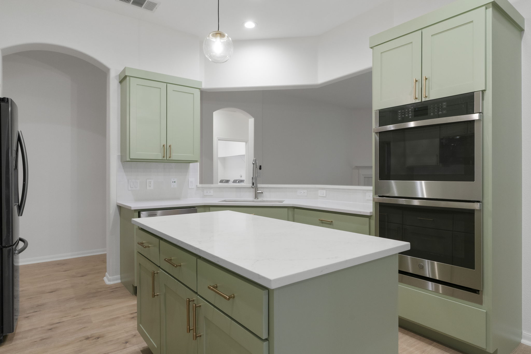 1333 Clary Sage Loop Round Rock, TX 78665 - Photo 8 of 34 Kitchen with green cabinetry, stainless steel double oven, a center island, freestanding refrigerator, and decorative light fixtures