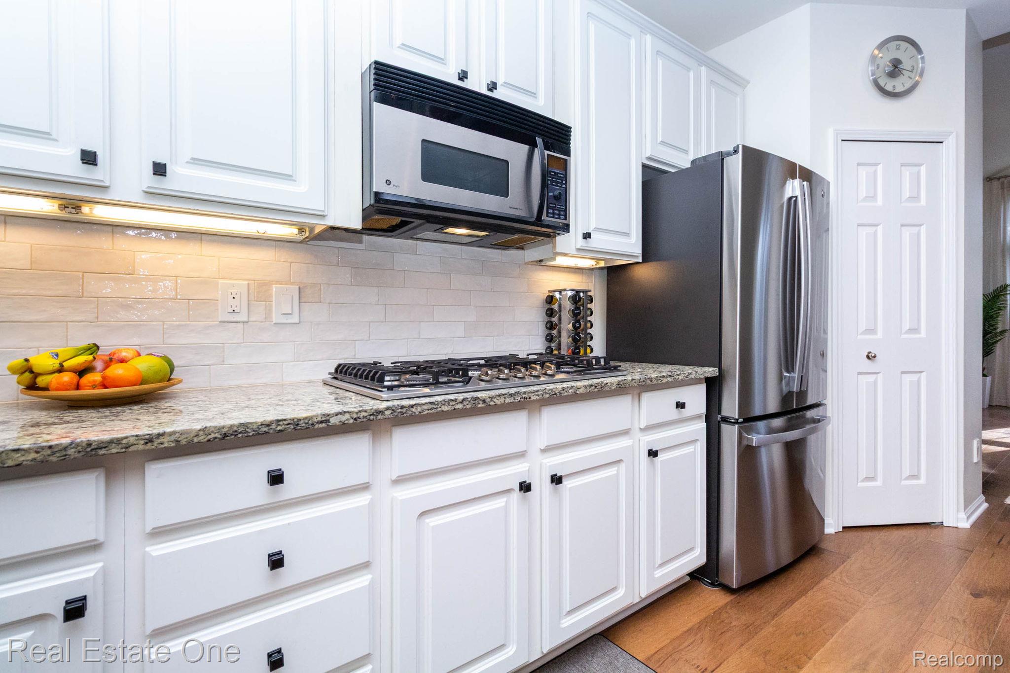 3585 Winding Brk Circle, Unit 89 Rochester, MI 48309 - Photo 19 of 59 Kitchen featuring white cabinetry, stainless steel appliances, light stone countertops, light wood-style flooring, and decorative backsplash