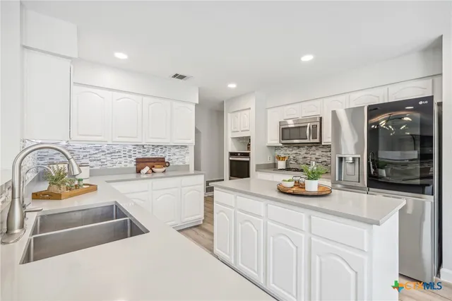 a kitchen with stainless steel appliances a refrigerator sink and white cabinets