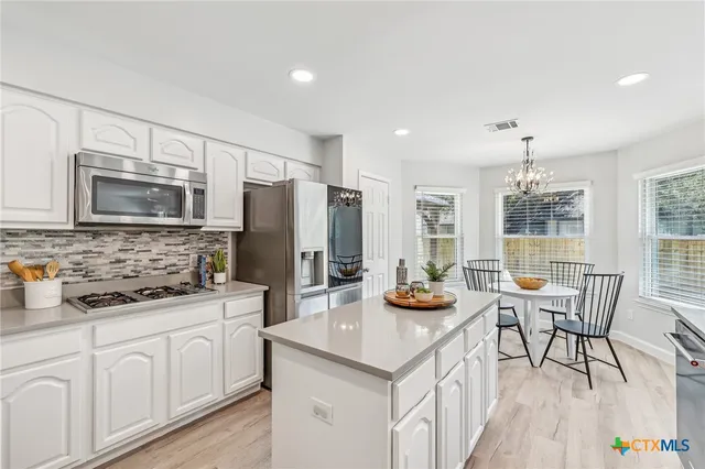 a kitchen with stainless steel appliances kitchen island granite countertop a sink and refrigerator