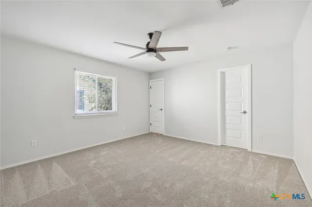 an empty room with windows and fan