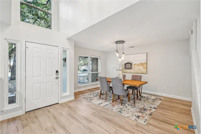 a dining room with wooden floor a glass table and chairs