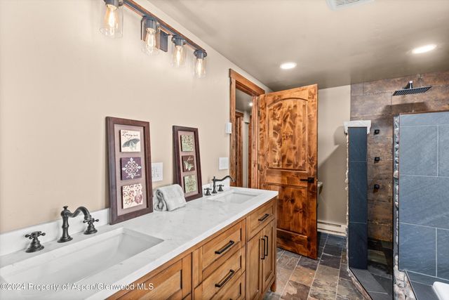 a bathroom with double vanity sink a mirror and a shower