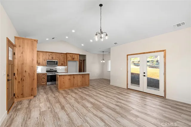 a large kitchen with kitchen island a stove a refrigerator a sink dishwasher with a dining table and chairs with wooden floor