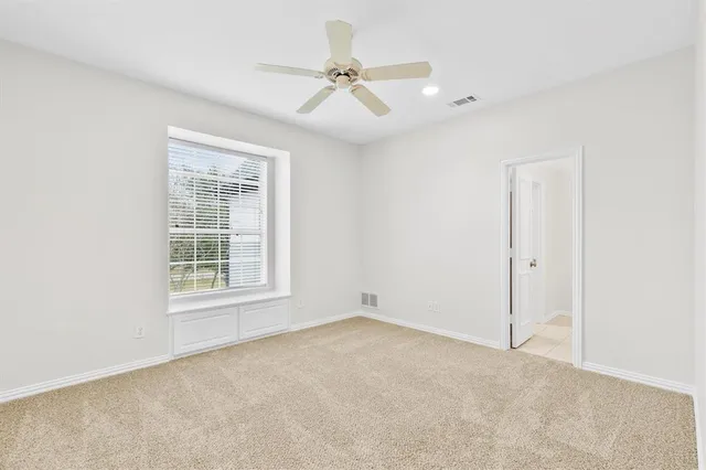 an empty room with windows and fan