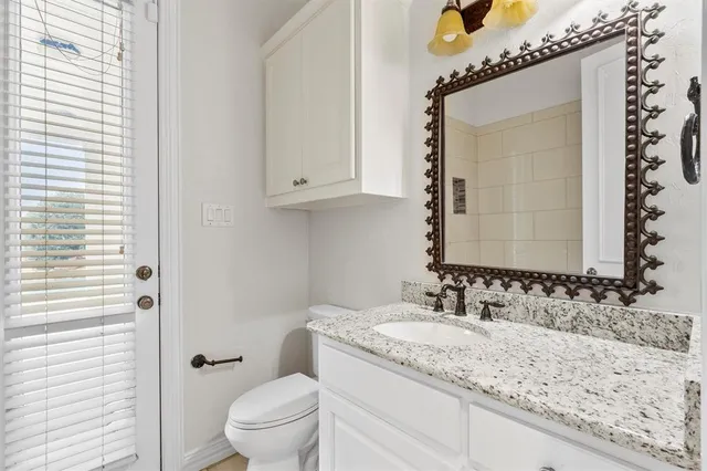 a bathroom with a granite countertop sink a toilet and a mirror