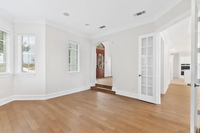 an empty room with wooden floor and windows