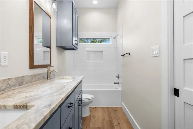 a bathroom with a granite countertop sink a toilet and bathtub