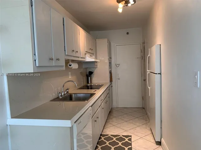 a kitchen with white cabinets and refrigerator