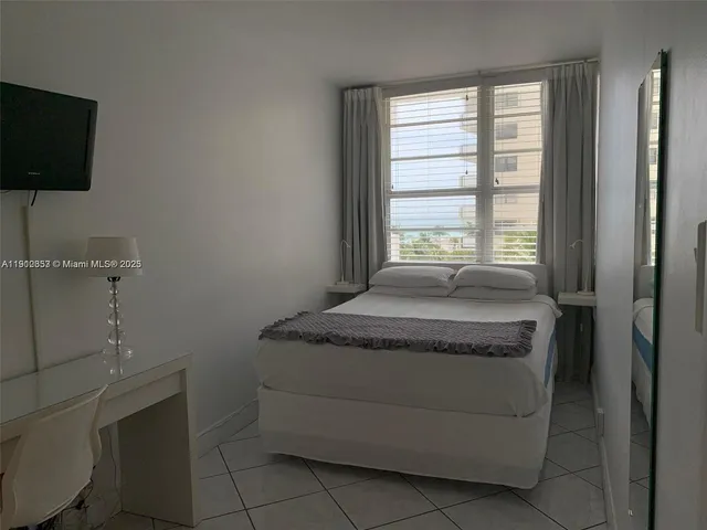 a spacious bedroom with a bed and a flat screen tv