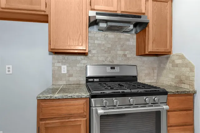 a kitchen with granite countertop stainless steel appliances white cabinets and a sink