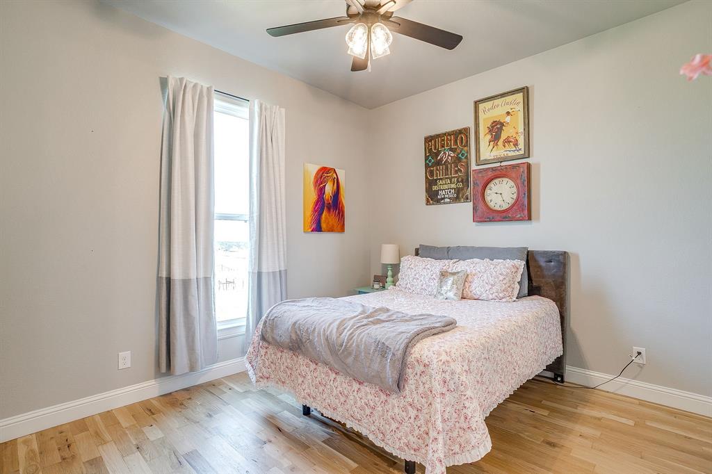 116 Aviara Ridge Road Poolville, TX 76487 - Photo 23 of 38 a bedroom with a bed and a chandelier
