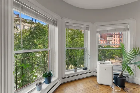 a view of a room with a large window and dining table with wooden floor