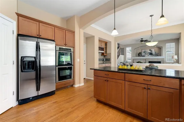 a kitchen with stainless steel appliances granite countertop a refrigerator a sink and a wooden floor