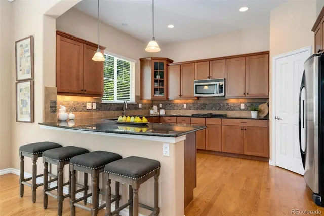 a kitchen with stainless steel appliances granite countertop a stove a sink dishwasher a refrigerator and a microwave oven with wooden floor