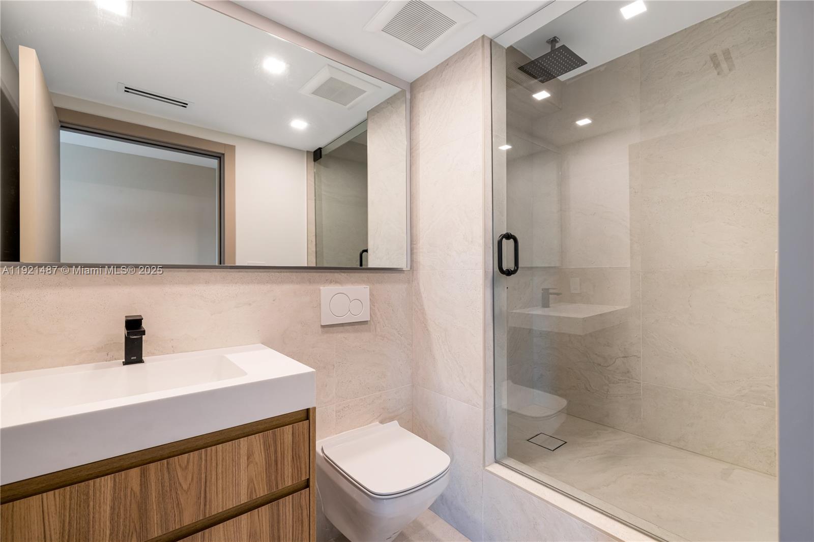 10155 Collins Avenue, Unit 202 Bal Harbour, FL 33154 - Photo 11 of 50 a bathroom with a toilet a sink and mirror