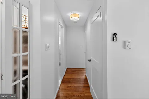 a view of a hallway with wooden floor and a bathroom
