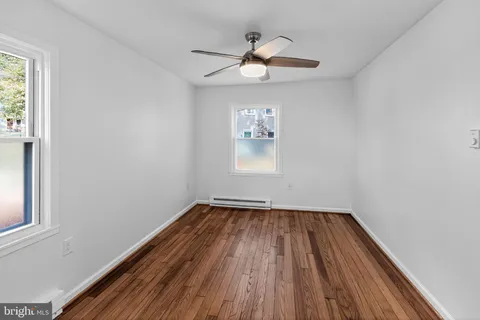 a view of empty room with wooden floor and fan