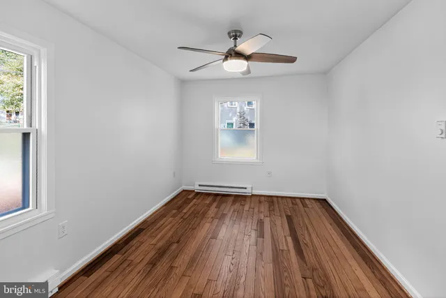 a view of empty room with wooden floor and fan
