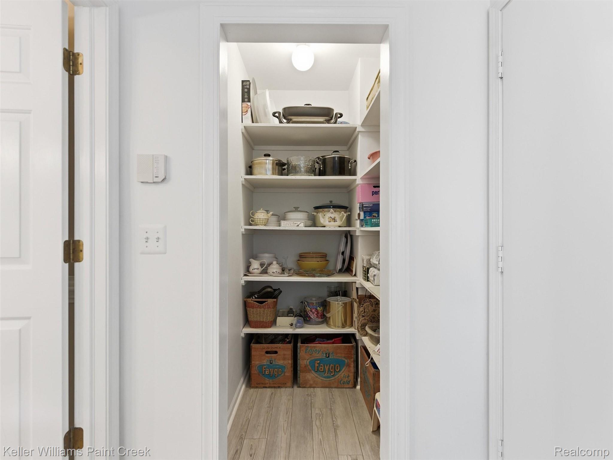 2842 Manorwood Road Troy, MI 48085 - Photo 44 of 72 Recessed pantry with custom shelving, light wood-finish flooring, and overhead lighting