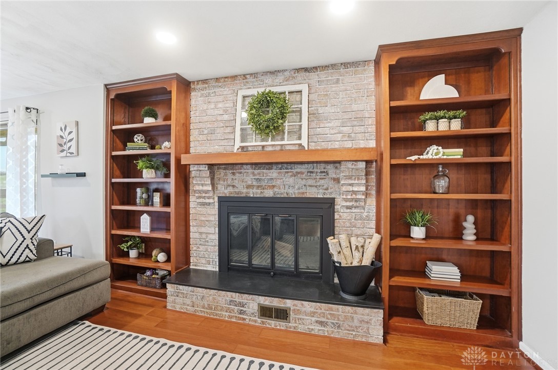 2848 Ellen Lane Dayton, OH 45430 - Photo 17 of 62 Warm and inviting living area features a brick fireplace, built-in bookcases, and rich wood flooring.