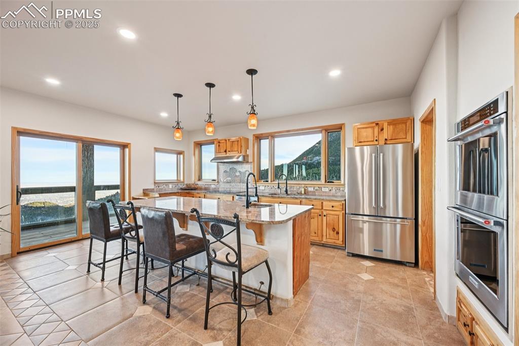 1417 Forest Road Manitou Springs, CO 80829 - Photo 14 of 50 a dining hall with stainless steel appliances granite countertop a stove a refrigerator a oven a sink with a dining table and chairs