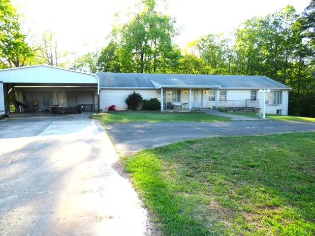 a view of a house with a yard and a large tree