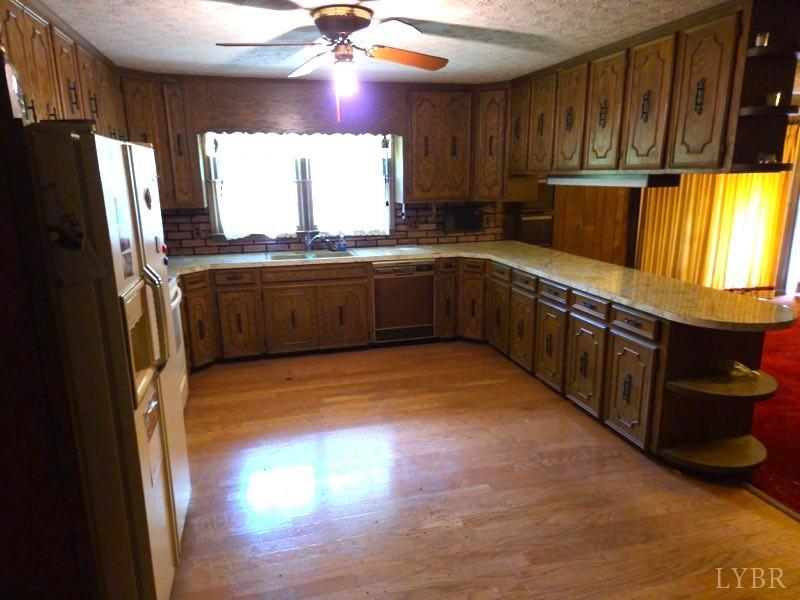 11420 Wards Road Rustburg, VA 24588 - Photo 10 of 34 a kitchen with stainless steel appliances granite countertop a refrigerator a sink dishwasher a stove and white countertops with wooden floor
