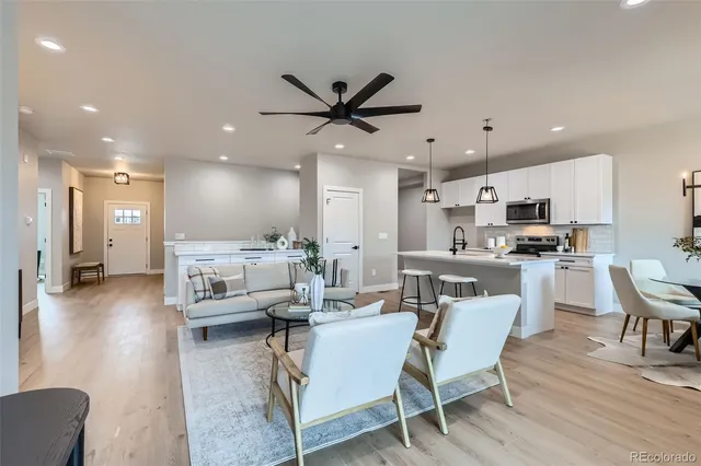 a living room kitchen with a dining table wooden floor and a view of kitchen
