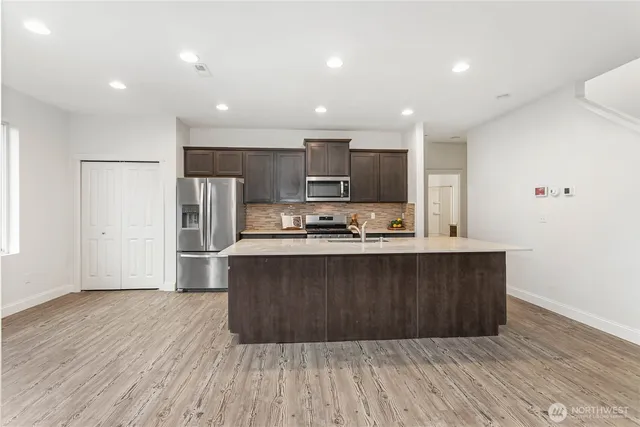 a large kitchen with stainless steel appliances a large counter top a stove and a refrigerator