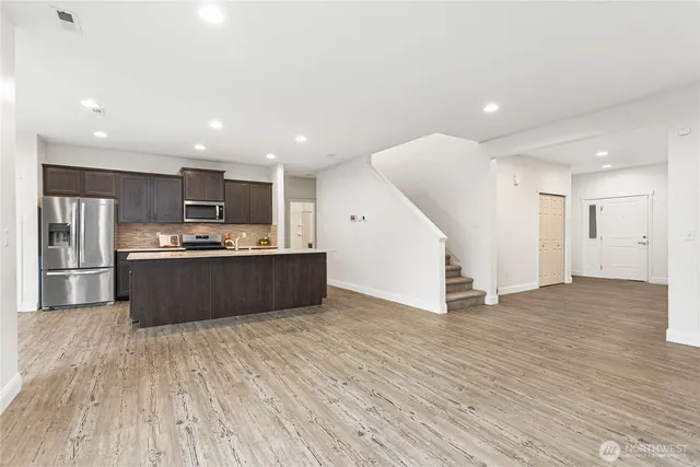 a large kitchen with stainless steel appliances a large counter top a refrigerator and a sink