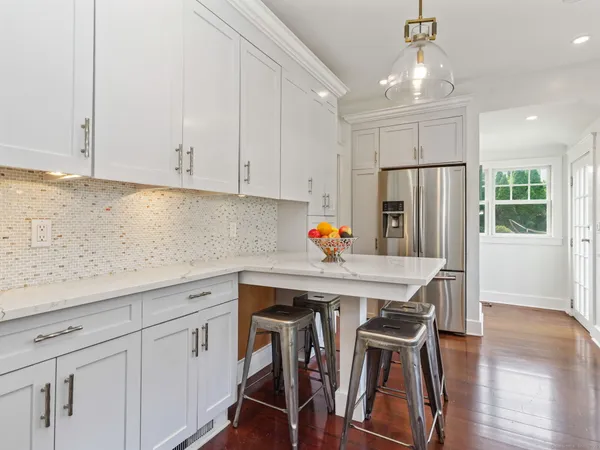 a kitchen with stainless steel appliances a white table chairs and a refrigerator
