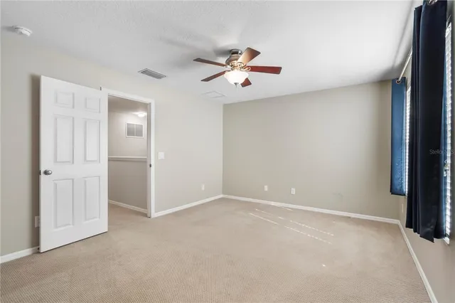 an empty room with windows and fan