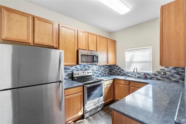a kitchen with stainless steel appliances granite countertop a refrigerator a sink a stove a washer dryer and cabinets