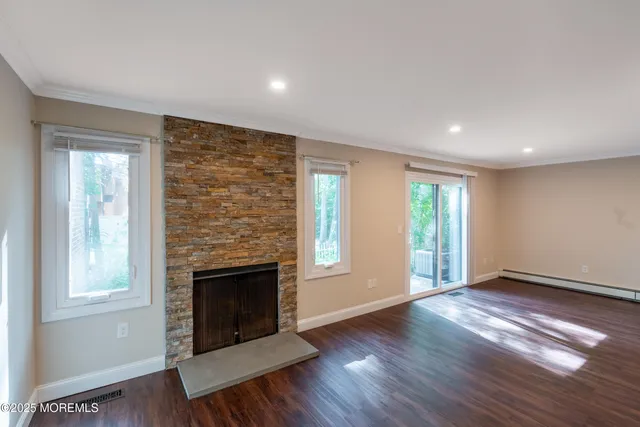 an empty room with wooden floor fireplace and windows