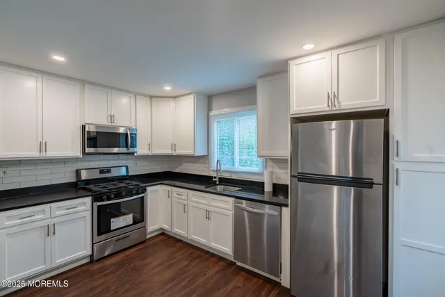 a kitchen with a refrigerator a sink and wooden floor