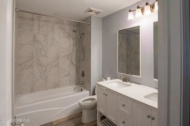 a bathroom with a granite countertop sink a toilet and shower