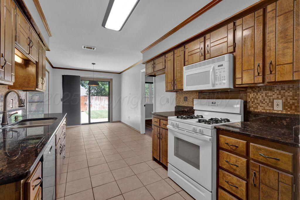 7935 Mitcham Drive Amarillo, TX 79121 - Photo 6 of 20 a kitchen with stainless steel appliances granite countertop a stove a sink and a microwave