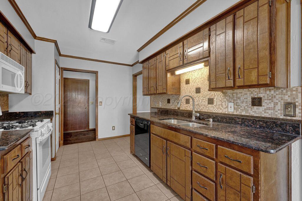 7935 Mitcham Drive Amarillo, TX 79121 - Photo 7 of 20 a kitchen with granite countertop a sink stove and refrigerator