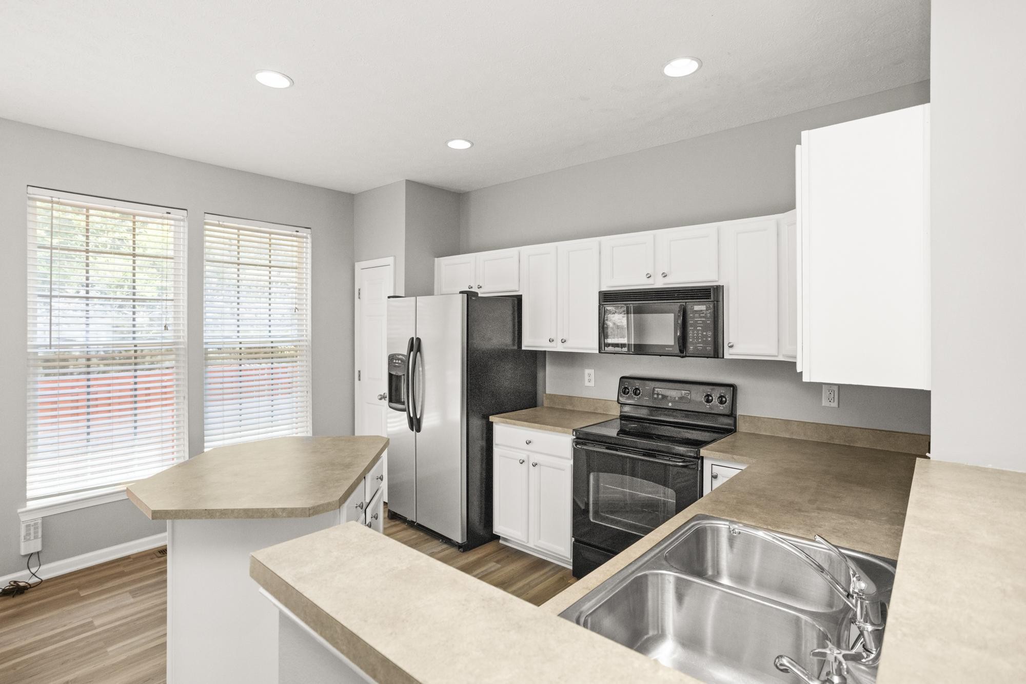 7277 Charlotte Pike, Unit 227 Nashville, TN 37209 - Photo 12 of 36 a kitchen with stainless steel appliances granite countertop a stove top oven a sink a refrigerator white cabinets and wooden floor