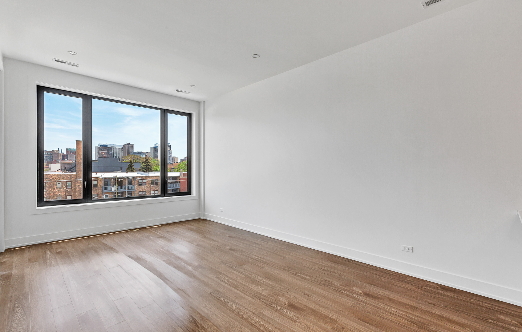 3312 North Halsted Street, Unit 2F Chicago, IL 60657 - Photo 2 of 17 a view of an empty room with wooden floor and a window