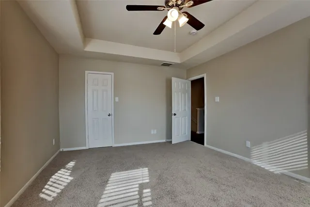 a view of an empty room with a chandelier fan