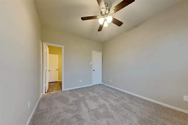 an empty room with a chandelier fan and a ceiling fan