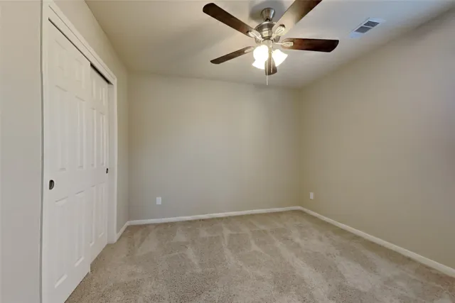 an empty room with a chandelier fan and windows
