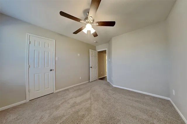 an empty room with closet and a ceiling fan