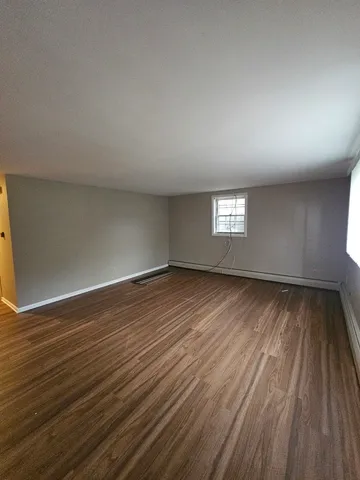 a view of empty room with window and wooden floor