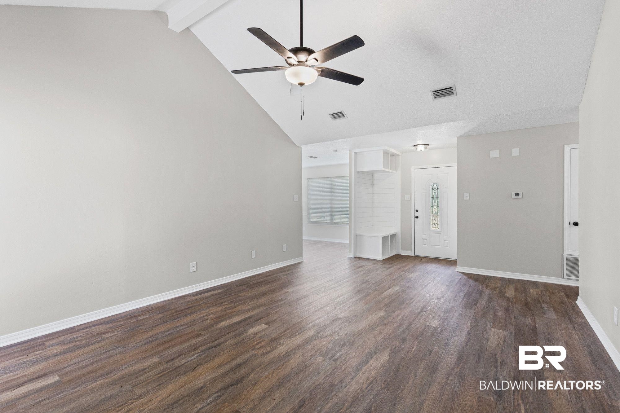 1301 Repoll Road Mobile, AL 36695 - Photo 4 of 21 Spacious room featuring vaulted ceilings, wood-finish flooring, a contemporary ceiling fan, and a built-in storage bench with shelving
