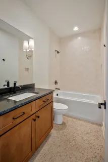a bathroom with a granite countertop sink a toilet and bathtub