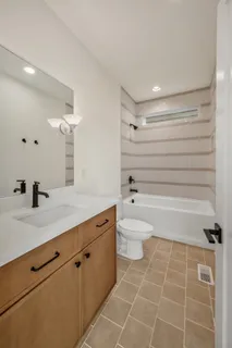 a bathroom with a bathtub shower sink vanity and a toilet